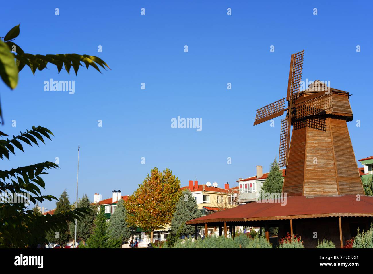Retro wooden windmill behind green leaves in Eskisehir Selale Park Eskisehir Turkey Stock Photo
