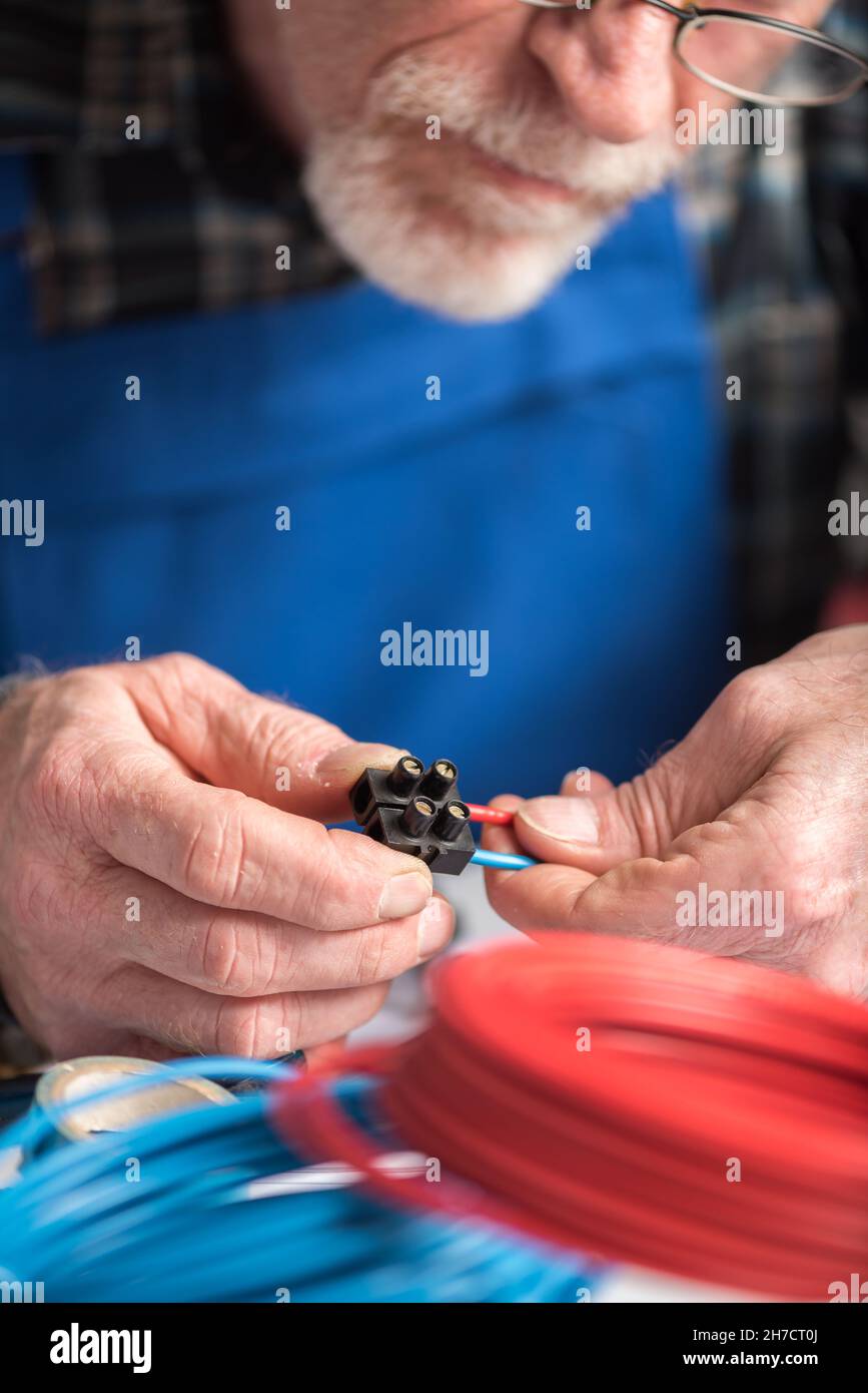 Senior electrician connecting wires in terminal block Stock Photo