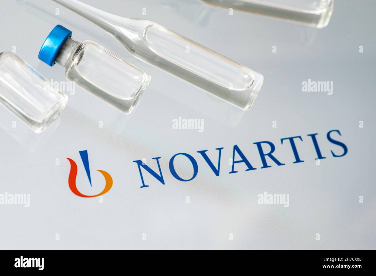 Vials of liquid on a white table and the logo of a large pharmaceutical company Novartis . March 15, 2021. Barnaul, Russia. Stock Photo