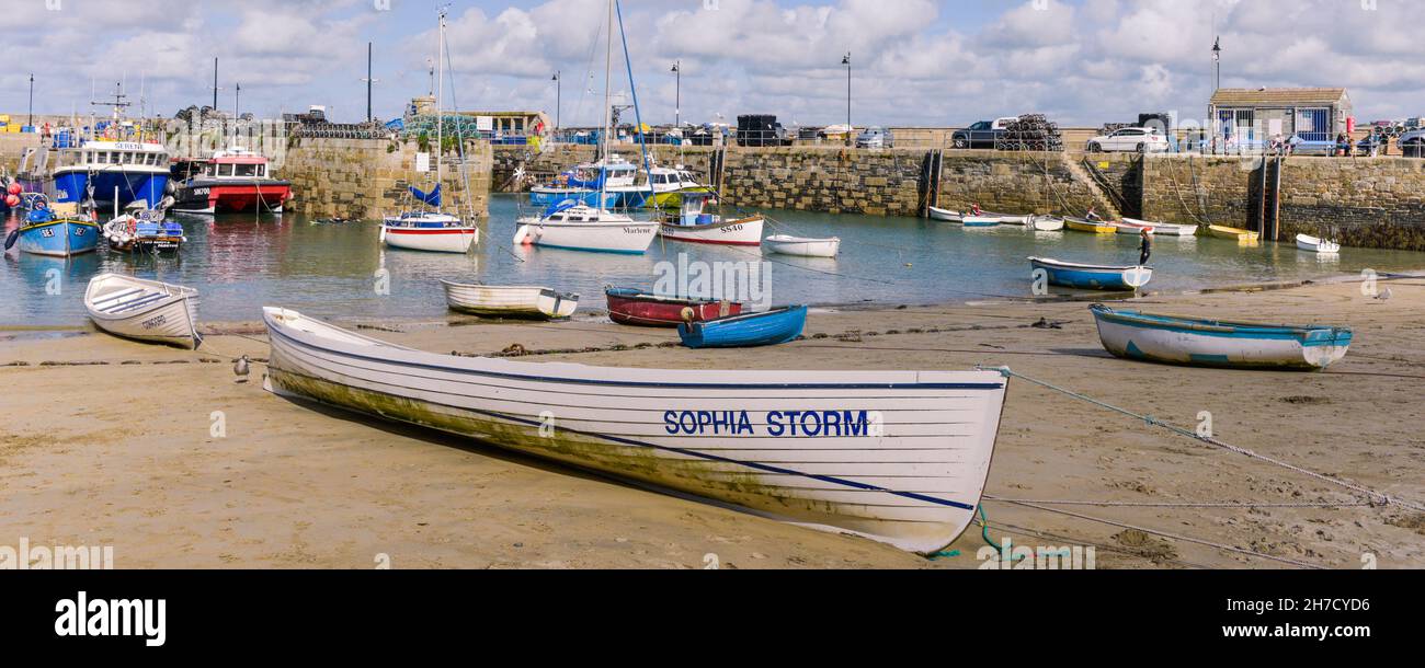 A panoramic image of traditional Cornish pilot gigs Sophia Storm and Concord beached on the beach in the historic picturesque working Newquay Harbour Stock Photo