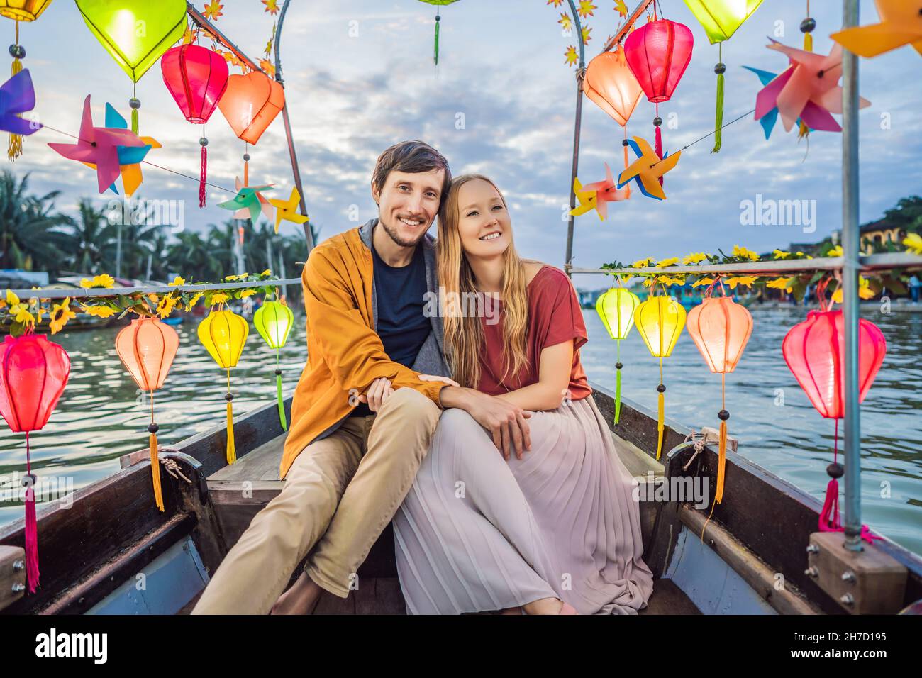 Happy couple of travelers ride a national boat on background of Hoi An ...