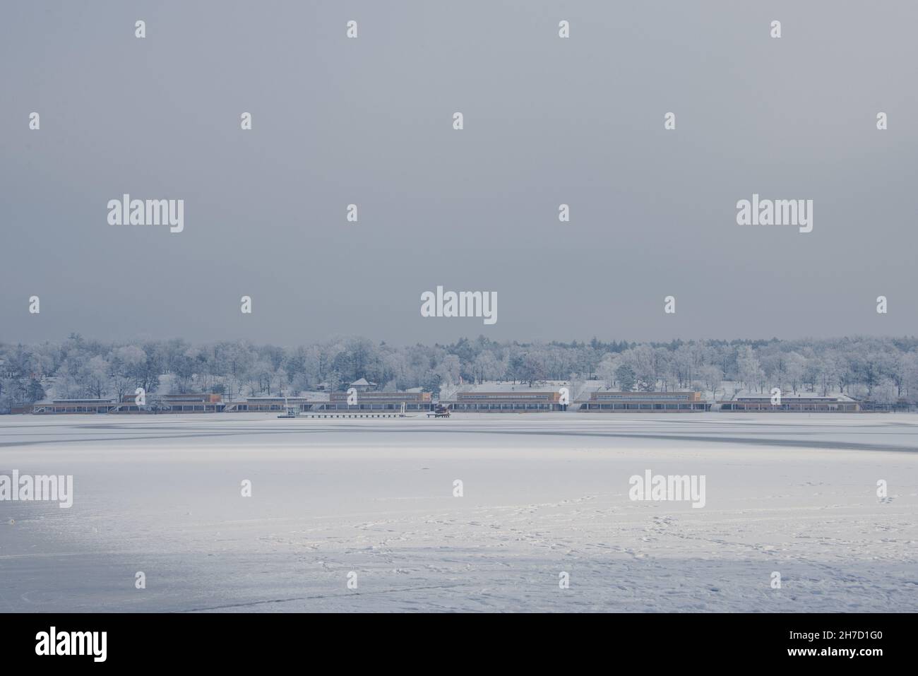 Grey and white: view across frozen lake Wannsee to the historic lido builidings. Stock Photo