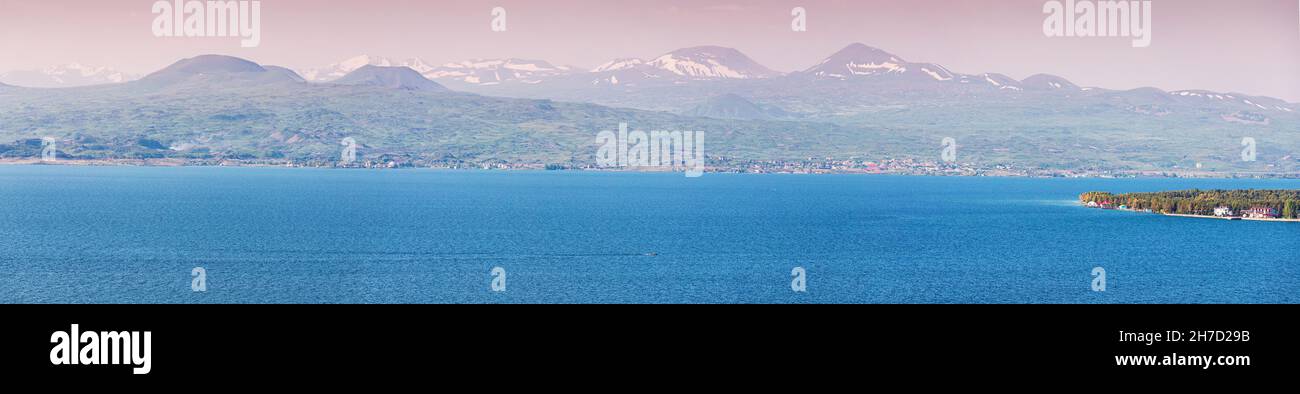 Panoramic view of famous Sevan lake with high mountain ranges with snow cap. Dramatic and scenic highland landscape. Tourist attractions in Armenia Stock Photo