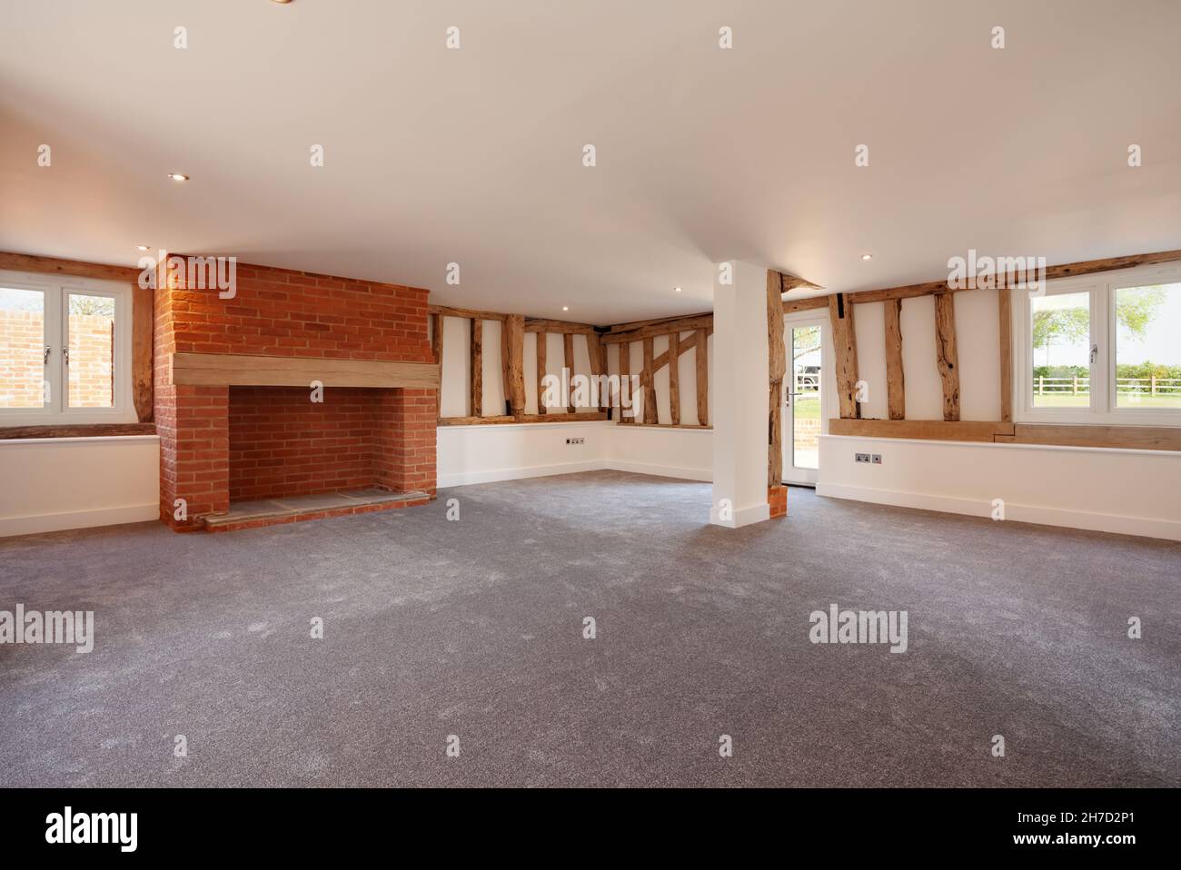 Great Sampford, Essex - April 16 2020: Empty living room within large recently converted barn with exposed timbers and inglenook fireplace. Stock Photo