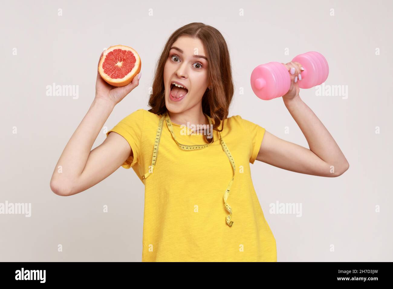 Excited female of young age with tape measure on shoulders holding