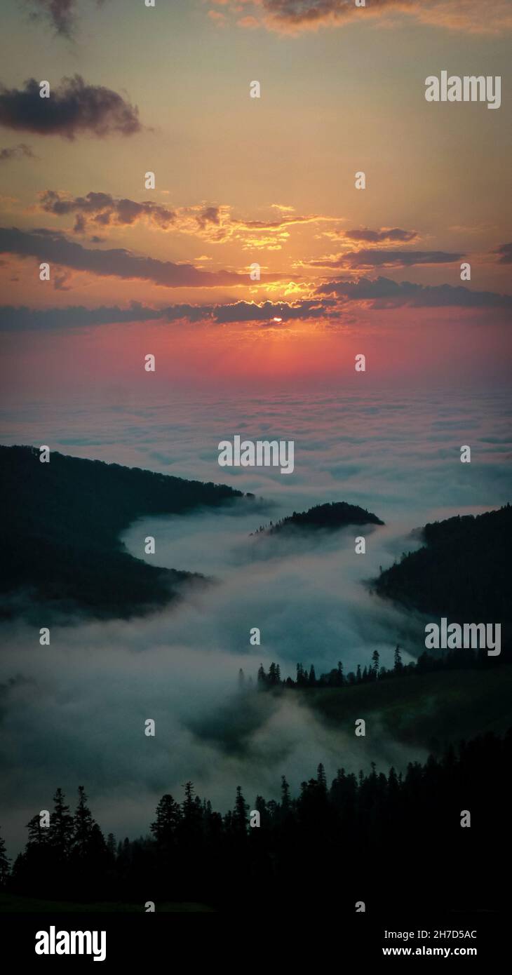 Aerial view of the green mountains covered in fluffy clouds gleaming ...