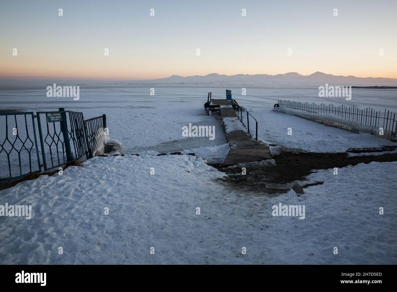Beautiful view of Lake Sevan covered with ice and snow-covered mountains in the background Stock Photo