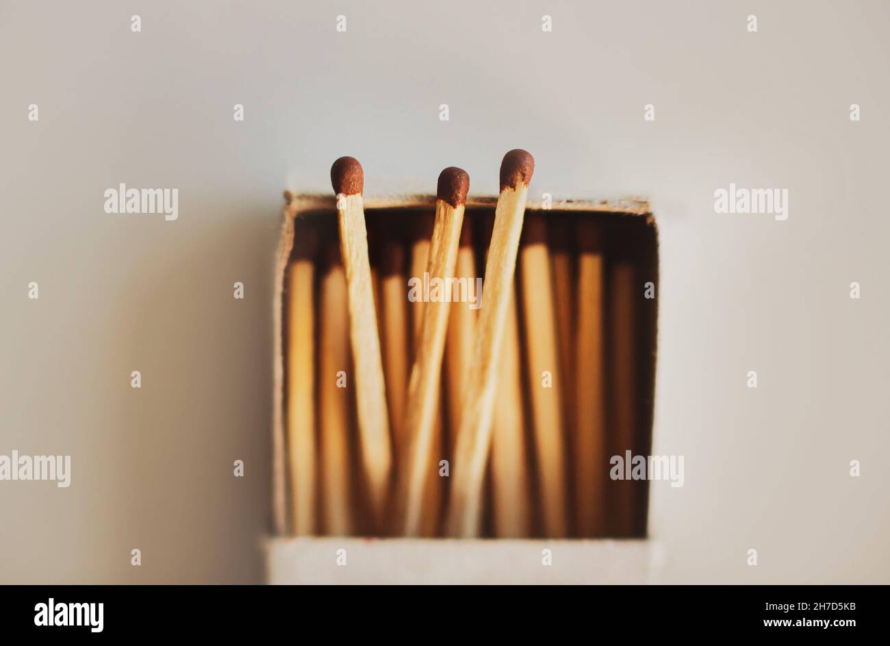 In a simple cardboard matchbox there are wooden matches with brown sulfur heads. Household items. Flammable objects. Macro. Three matches stick out of Stock Photo