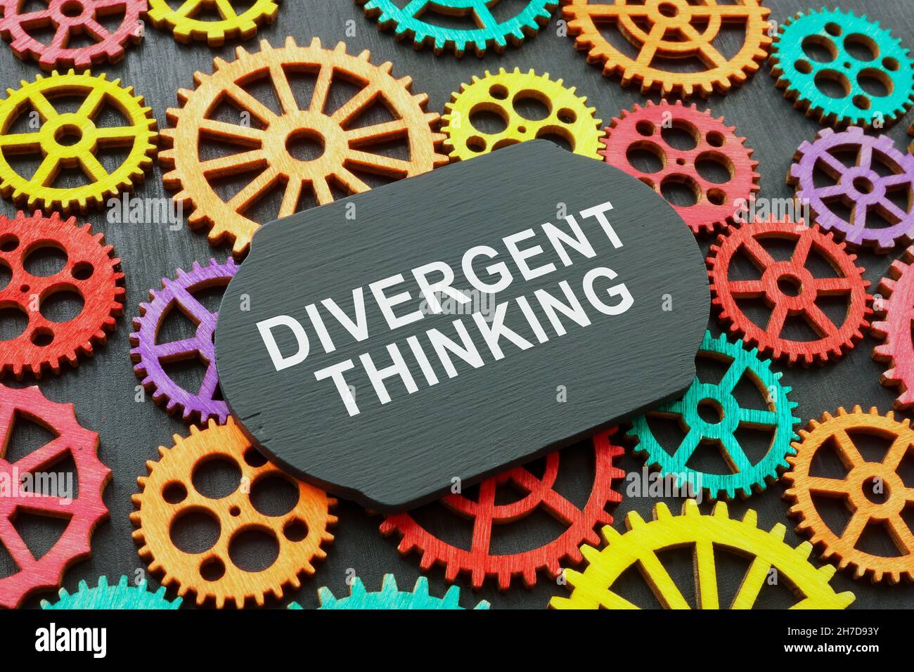 Divergent thinking words on the board and gear wheels. Stock Photo