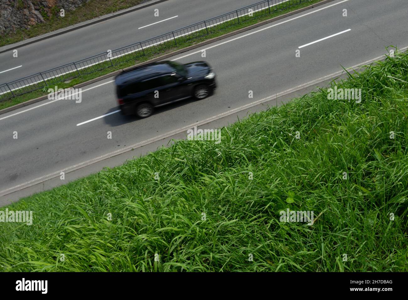 Background with road and car, roadsides overgrown with green grass. Stock Photo