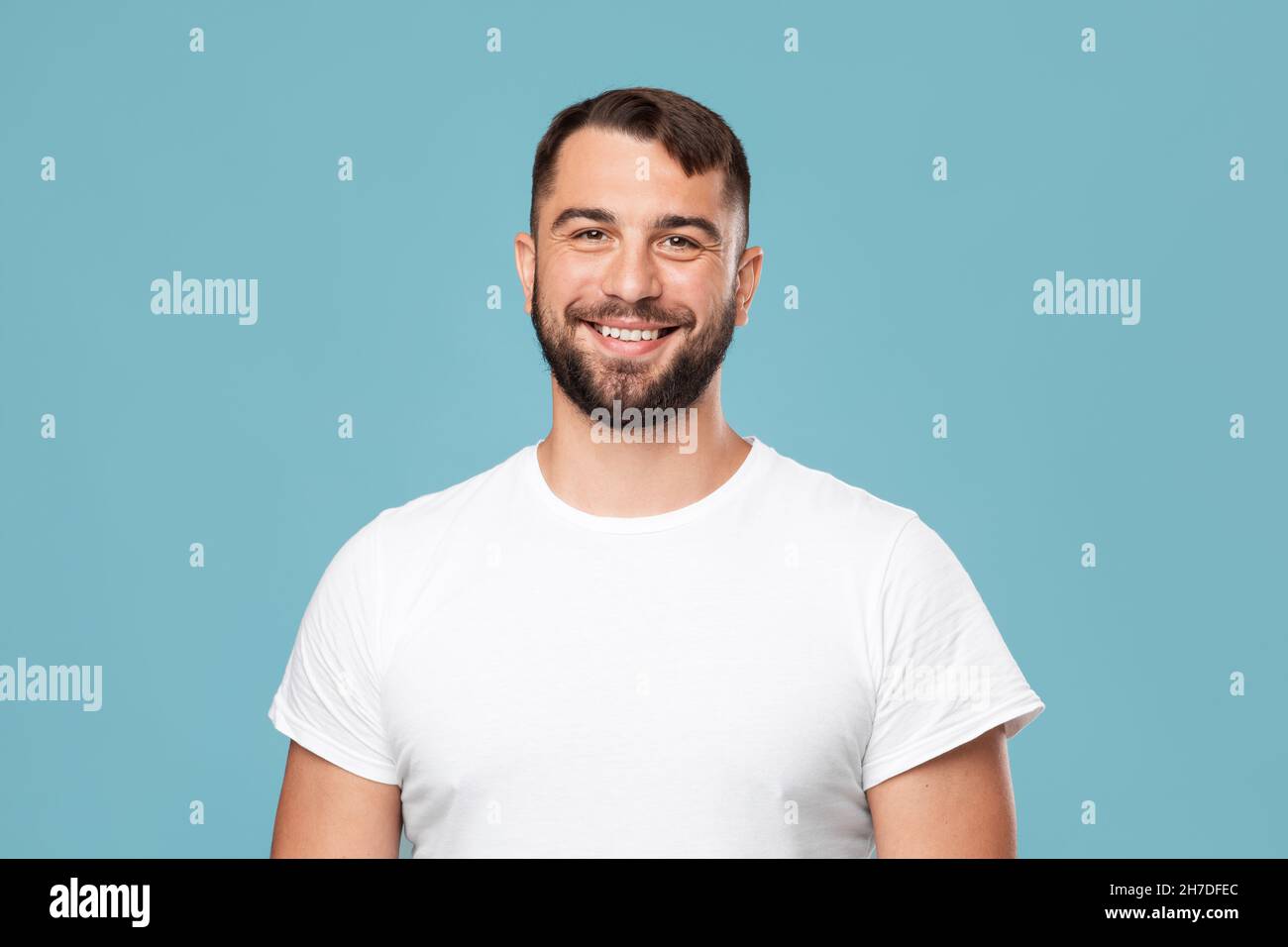 Happy handsome mature caucasian guy with beard in white t-shirt looking at camera Stock Photo