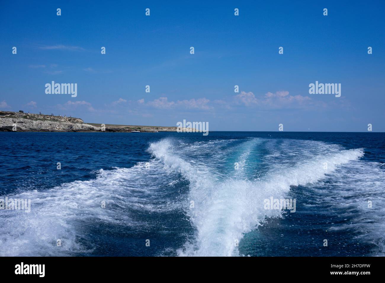 White foam trail from the movement of the boat on a blue background. Travel by sea. Stock Photo