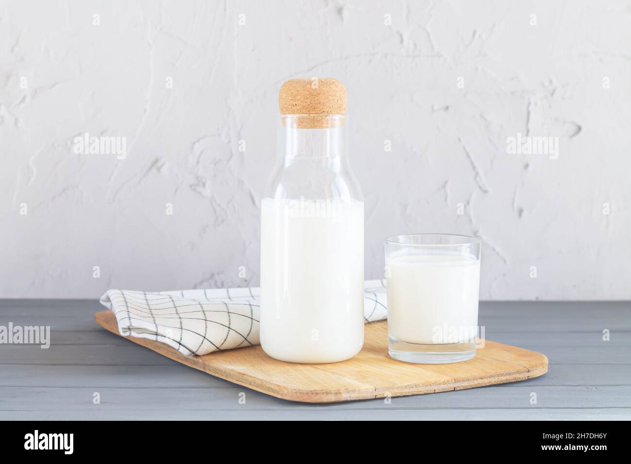 Glass jar with cork of homemade yogurt, kefir, buttermilk or natural fermented milk next to glass of milk on kitchen table. Healthy probiotic dairy dr Stock Photo