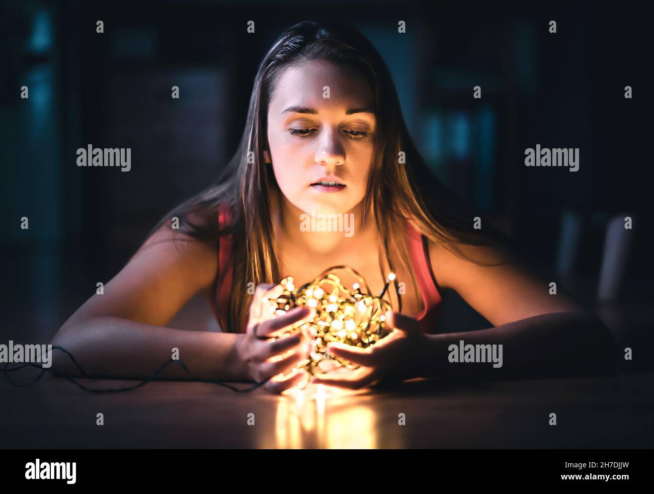 Woman with christmas light. Hope, despair and emotion. Portrait of a model with beautiful face in dark home at night. Magical mystery fantasy dream. Stock Photo