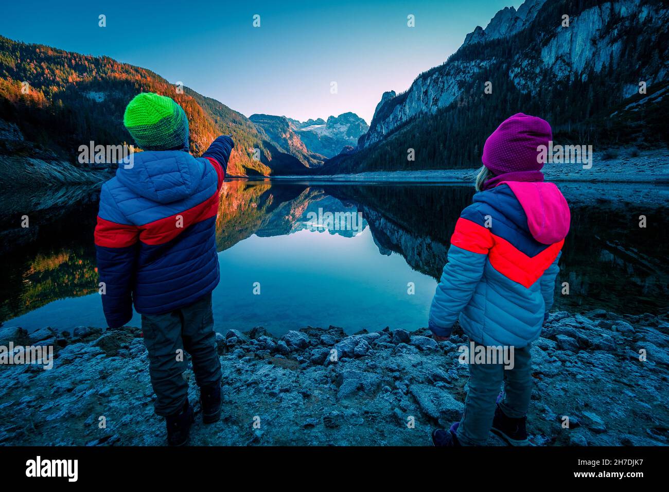 Kids looking at view of the 'Gosau-Kamm' mountain range and the Dachstein glacier reflecting on the Gosausee lake, Gosau, Salzkammergut, OÖ, Austria Stock Photo