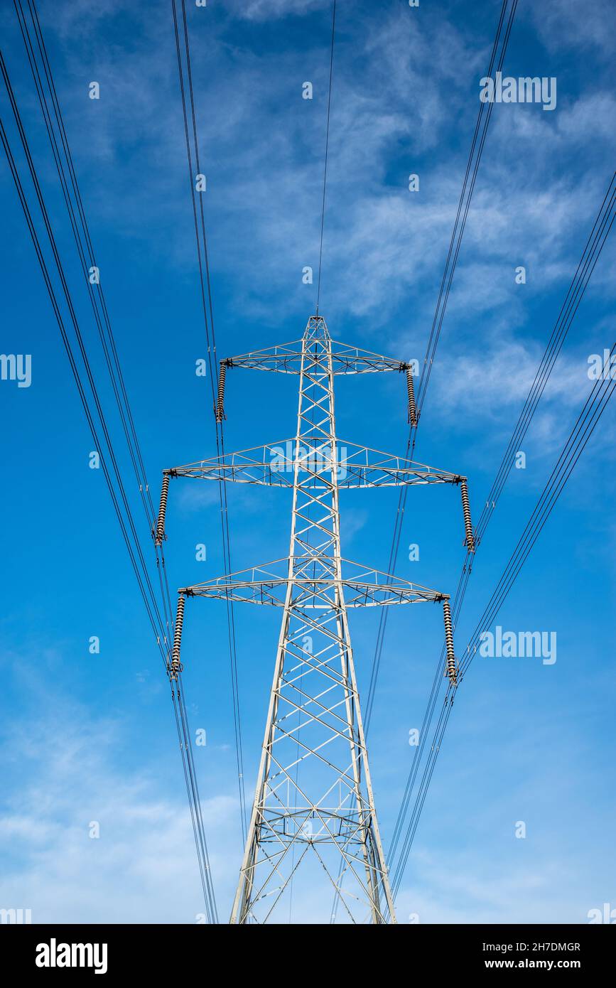 Large grey electricity pylon on sunny day with blue sky background. Stock Photo