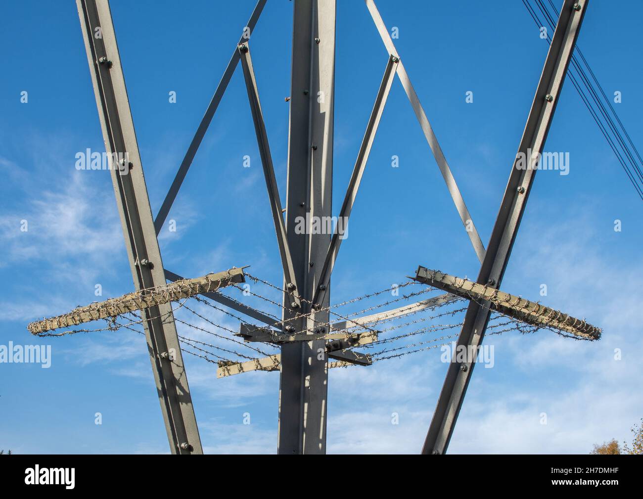 Anti climbing guard on electricity pylon with barbed wire on clear day with blue sky. Stock Photo