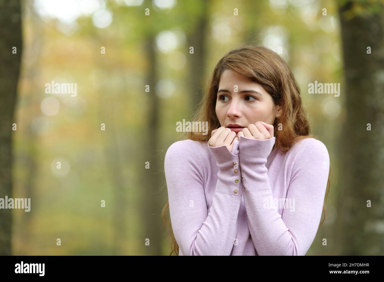 Scared woman looking at side walking alone in a park Stock Photo