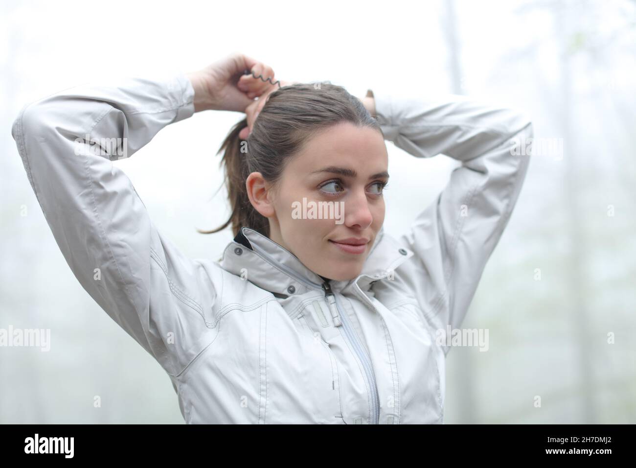 Happy trekker doing ponytail in a foggy forest Stock Photo