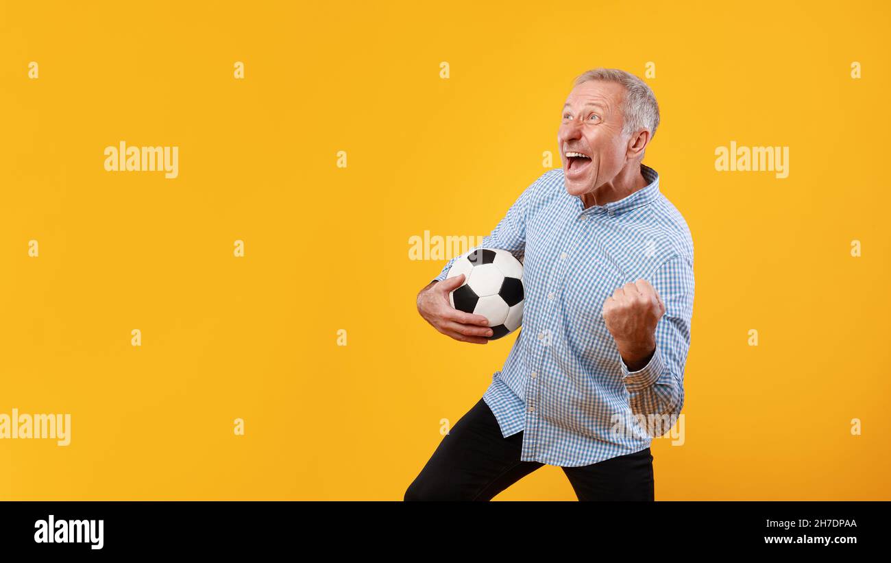Mature man posing with soccer ball on yellow background Stock Photo - Alamy