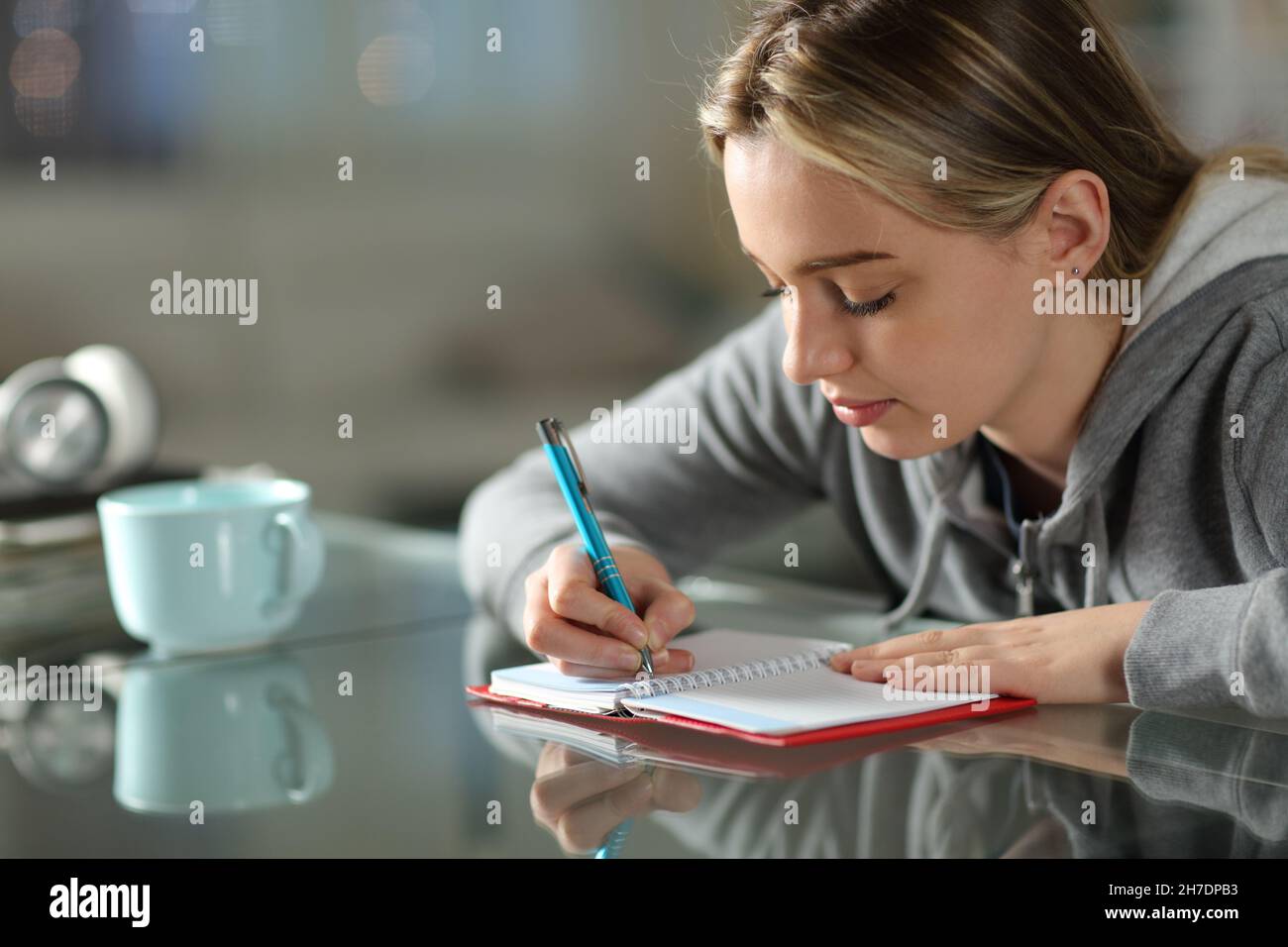 Concentrated student writing on paper agenda in the night at home Stock Photo