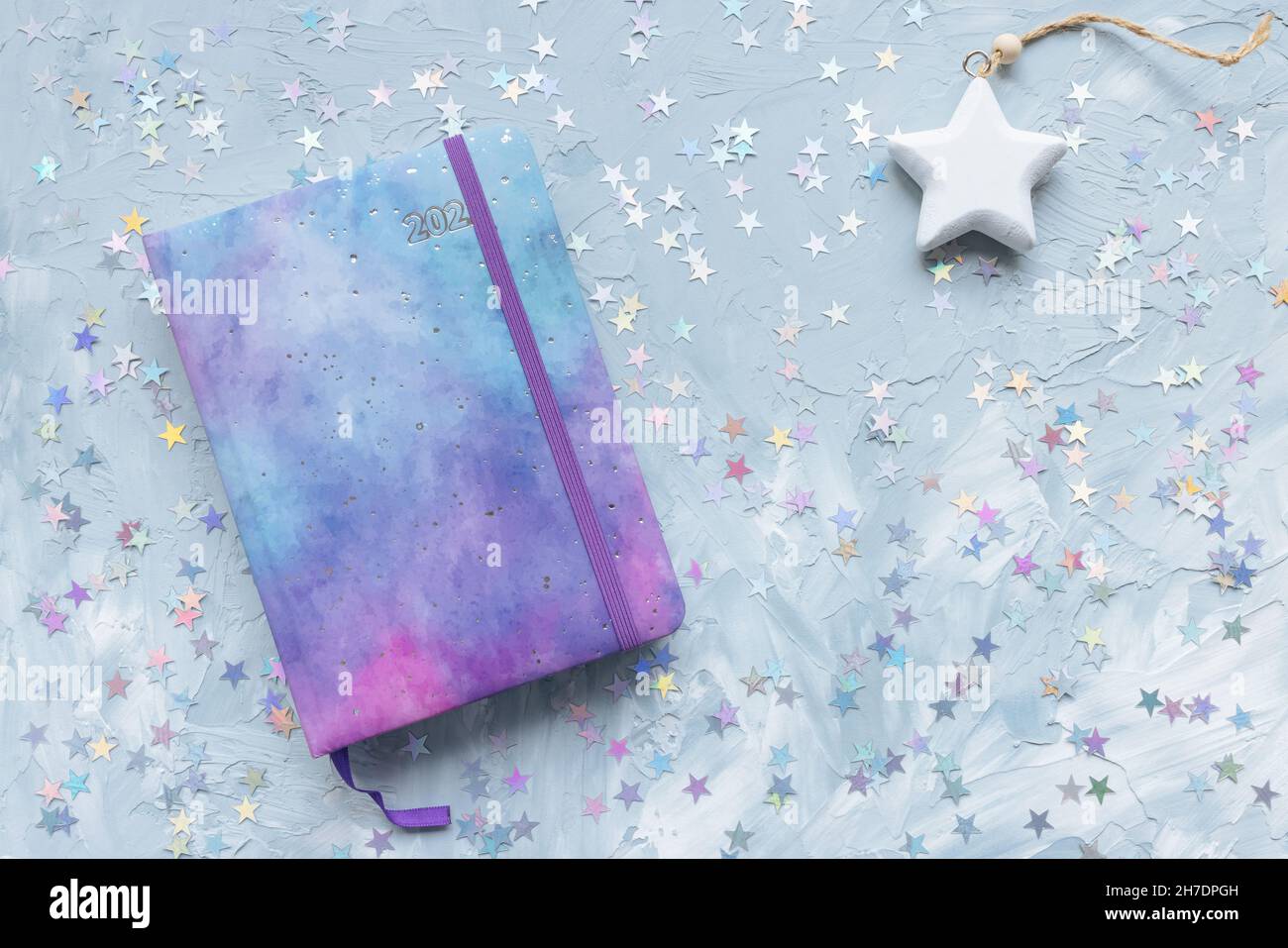 2022 yearly journal, chocolate and stars decoration on desk workspace, blue background. Winter holidays Christmas and New Year To Do List and lifestyle concept. Flat lay, top view, copy space Stock Photo