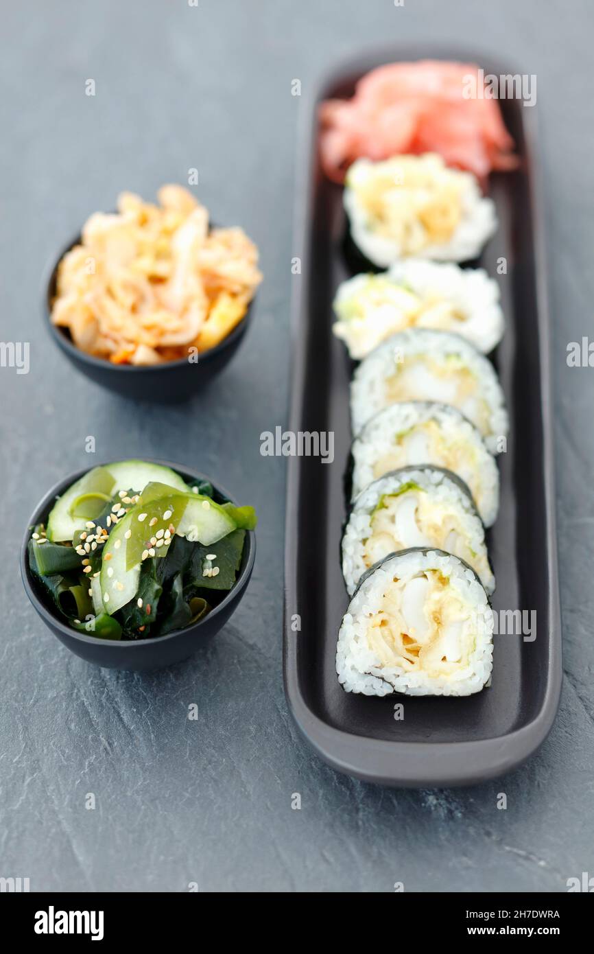 Sushi with squid in tempura, wakame and kimchi salads Stock Photo