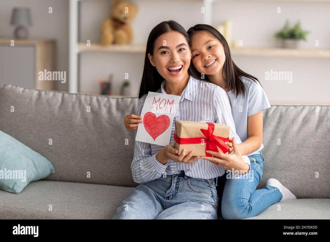 Mother's Day gift. Happy asian girl greeting young surprised mom, giving  her handmade card and wrapped gift box Stock Photo - Alamy