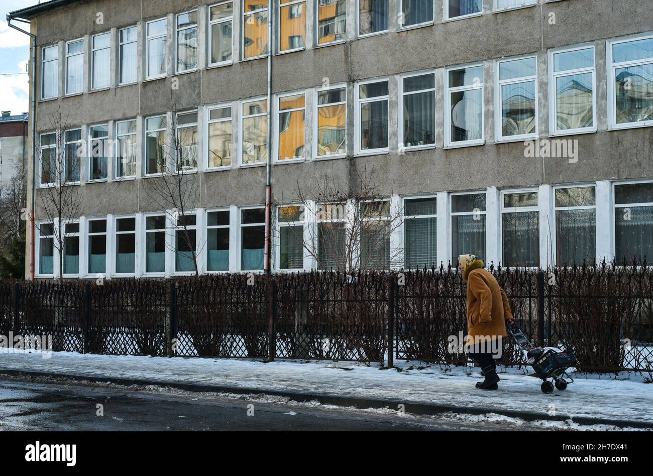 an old woman of retirement age with a bag on wheels walks alone along the street near the hospital, a lonely pensioner, kovid19, walking in the fresh Stock Photo