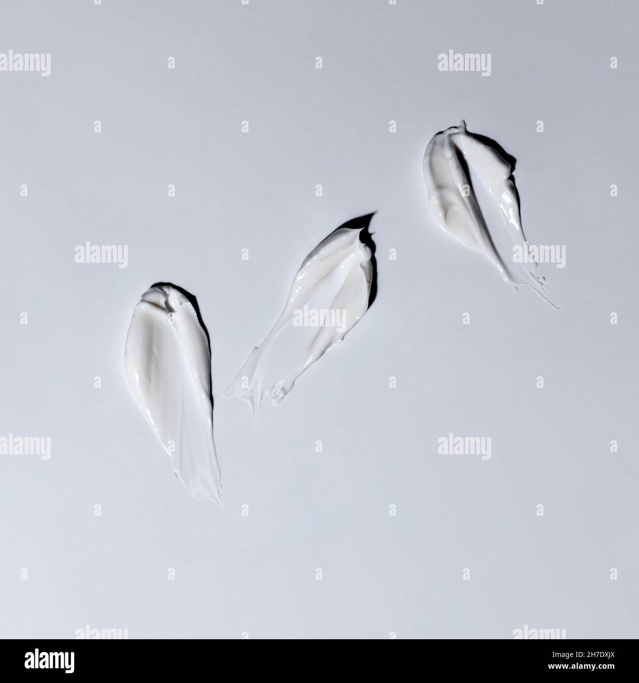 Sample of white cosmetic cream, drops of gel and foam on a gray background. Stock Photo
