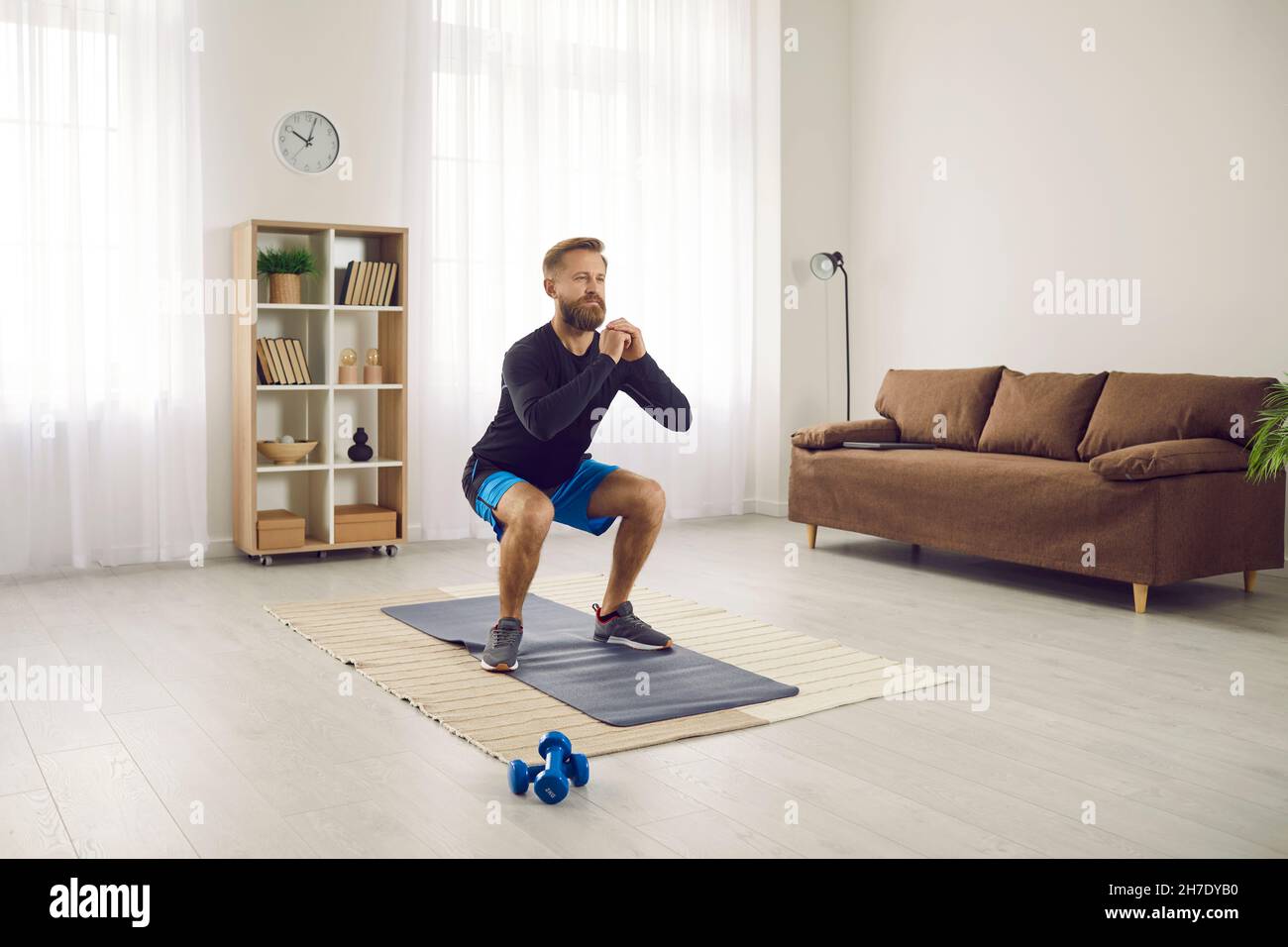 Portrait of active focused millennial man doing morning sports at home to keep fit. Stock Photo