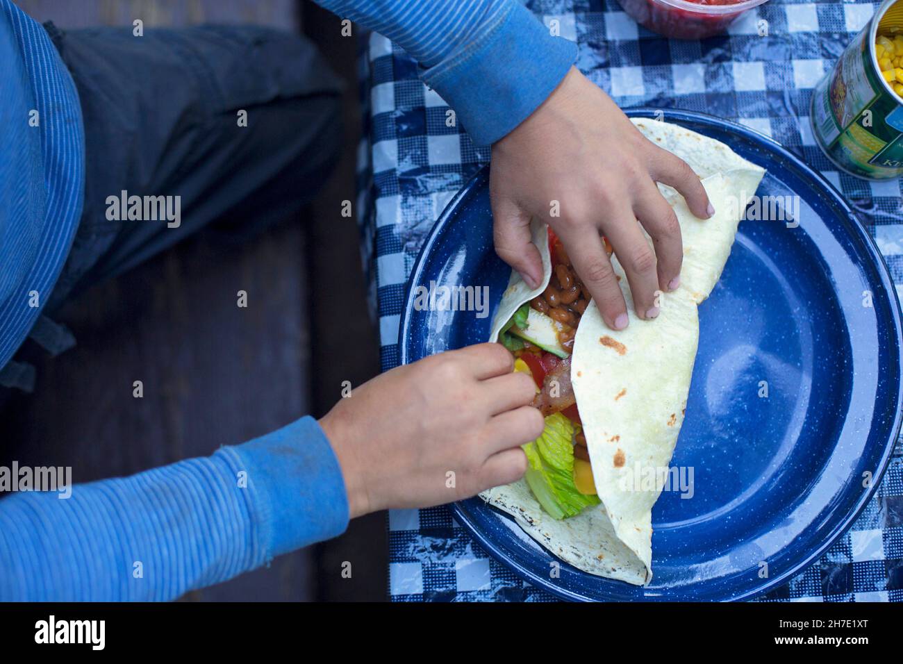 A child's hands rolling a filled burrito Stock Photo