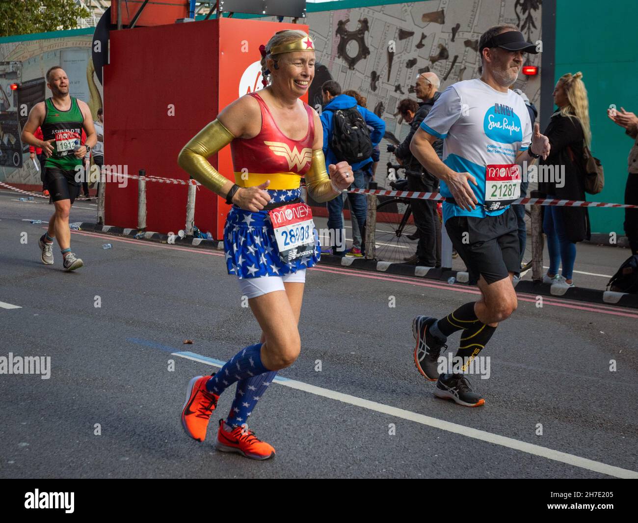 Woman running dressed as Wonder Woman, Virgin Money London Marathon 2021 at the 25 mile point, Victoria Embankment. Stock Photo