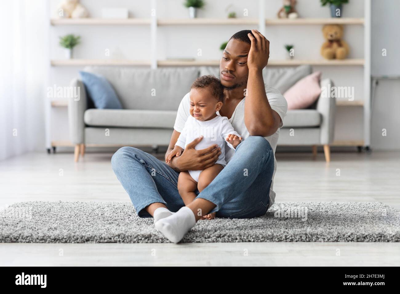 Daddy Blues. Stressed Young Black Father Sitting With Crying Infant Baby Stock Photo