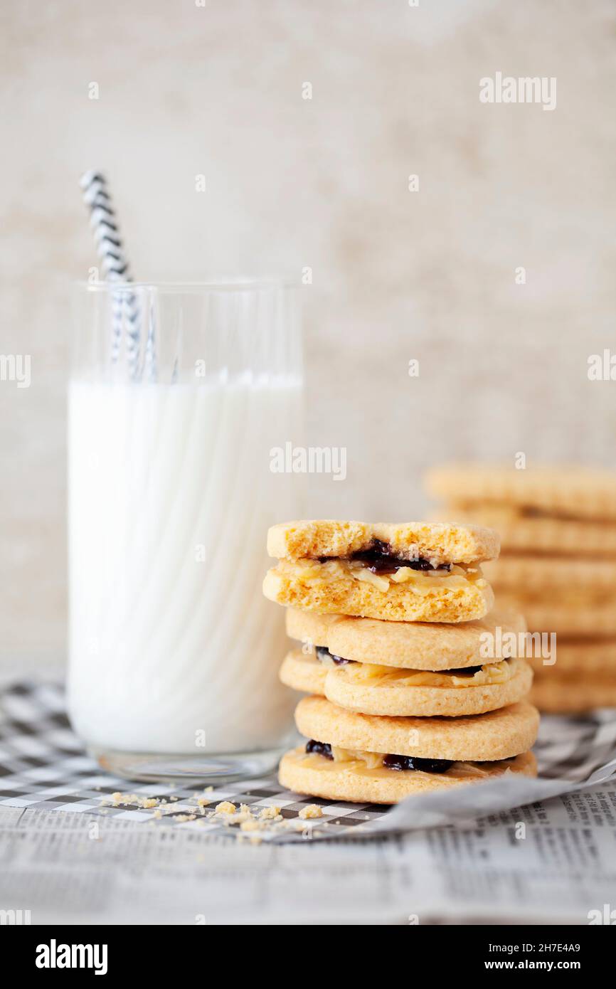 A stack of jam and cream biscuits with a glass of milk Stock Photo Alamy