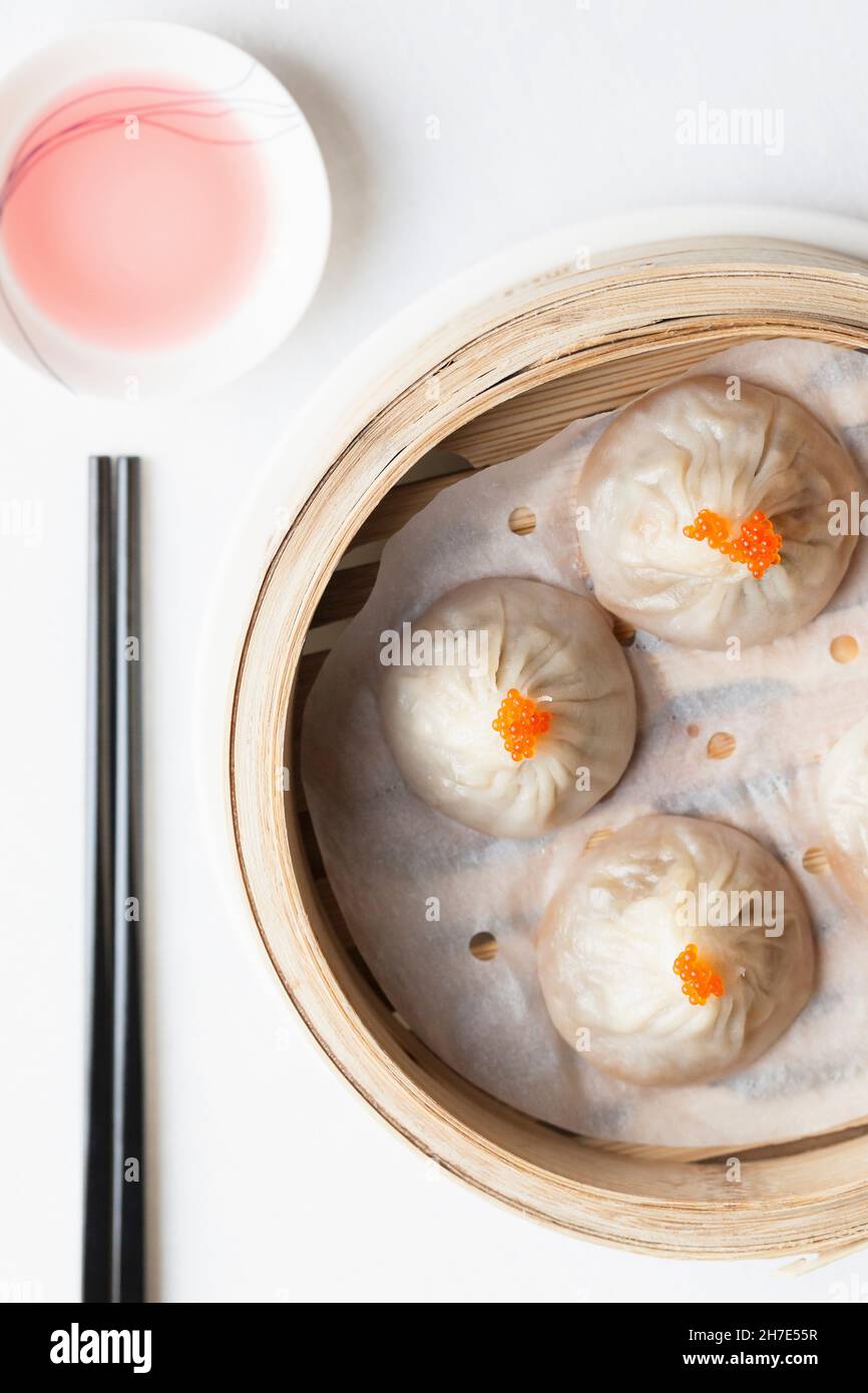Steamed Chinese dumplings with fish roe in bamboo steaming basket with chopsticks and dipping sauce Stock Photo