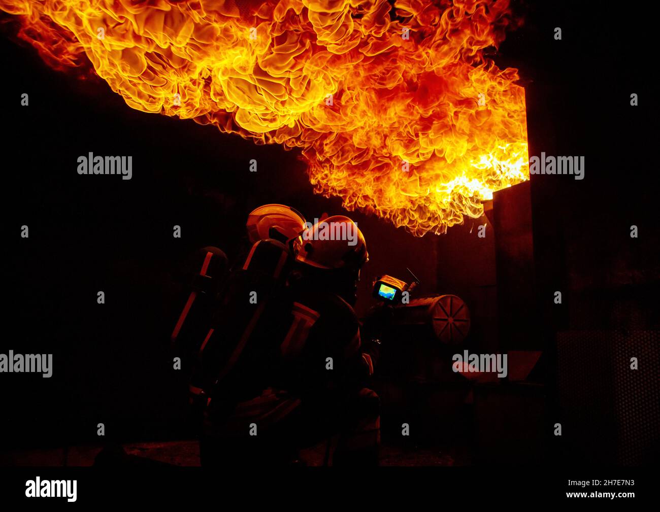 Two firefighters in a burning house full of flames while trying to put ...