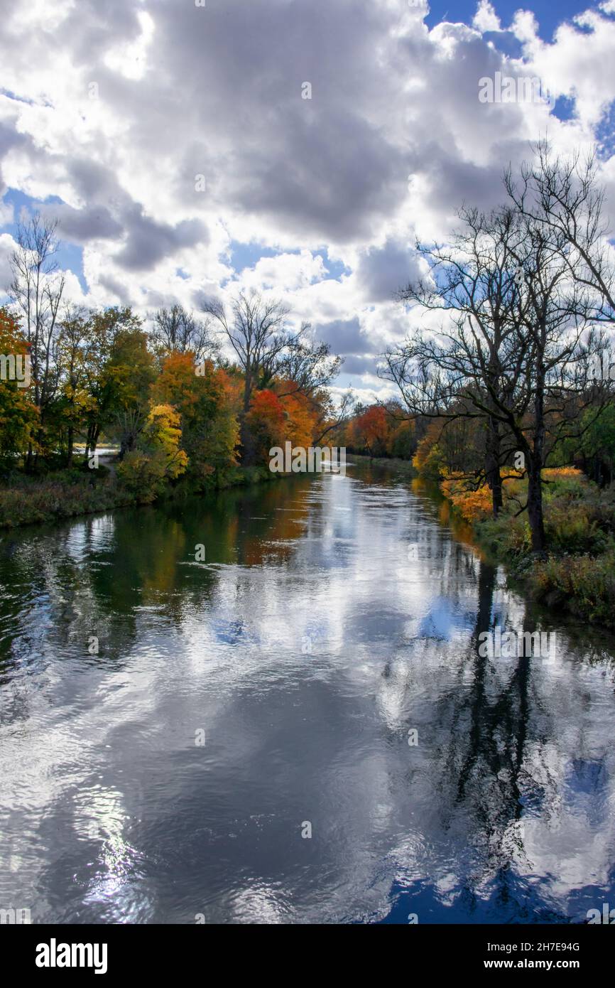 Cloudy blue sky and the warm colors of the autumn around the river Stock Photo