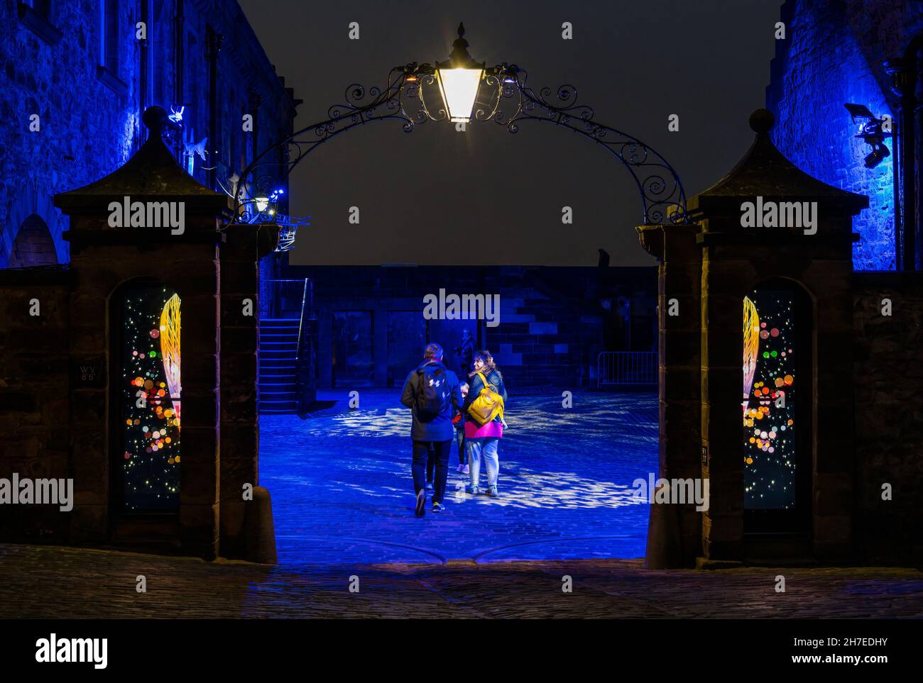 Family entering courtyard with old fashioned lamp lit at night, Castle of Light event, Edinburgh Castle, Scotland, UK Stock Photo