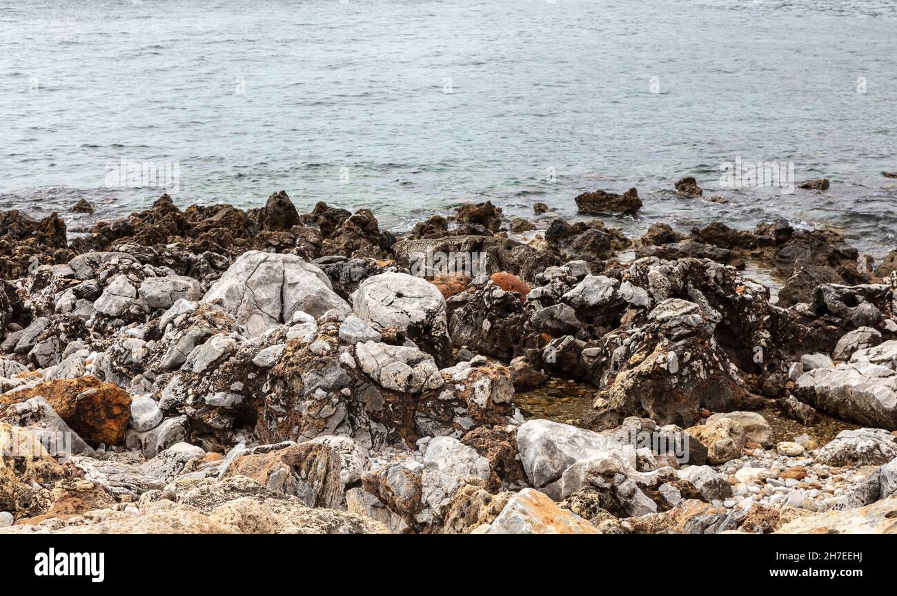 Empty rocky beach with dark and white rough rocks blue calm sea at ...