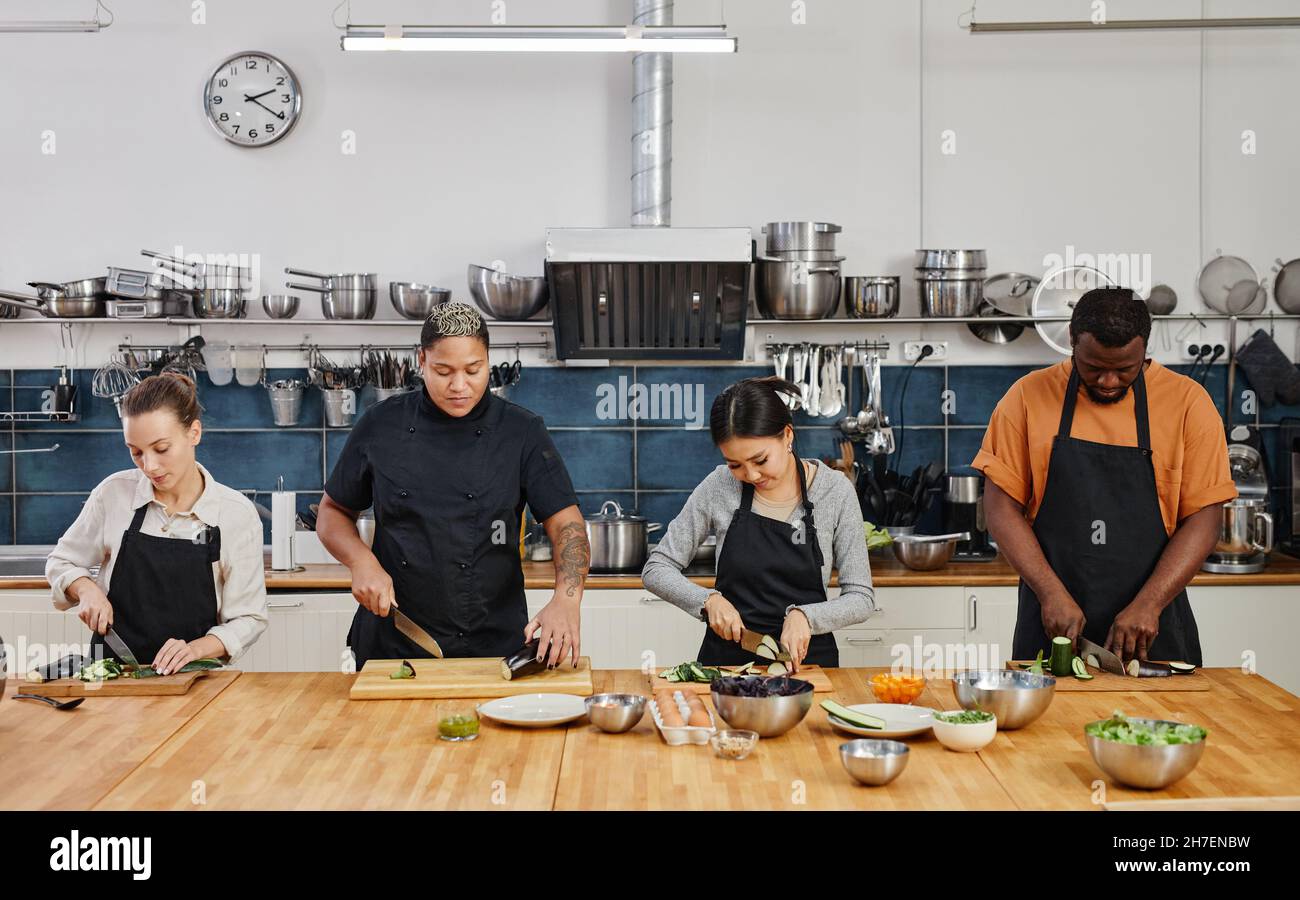 Waist up portrait of diverse group of people cutting vegetables in ...