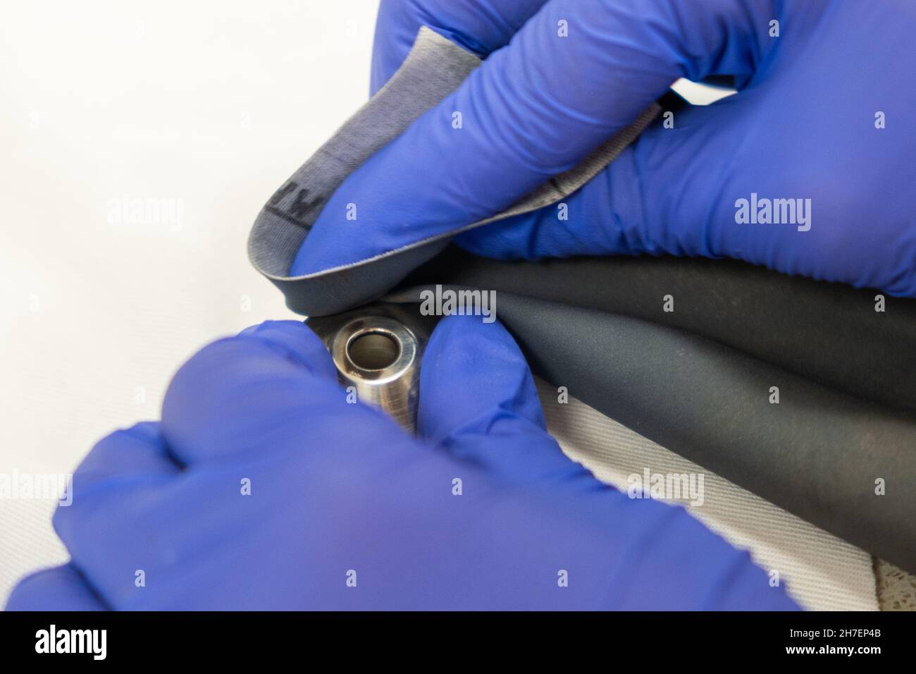 Close up hands in rubber gloves clean metal detail with sandpaper.  Stock Photo