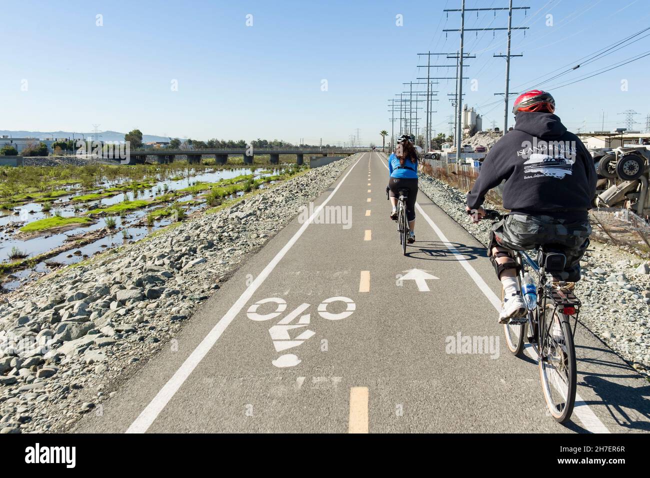 Couple riding on a bike path that follows the San Gabriel River Stock Photo