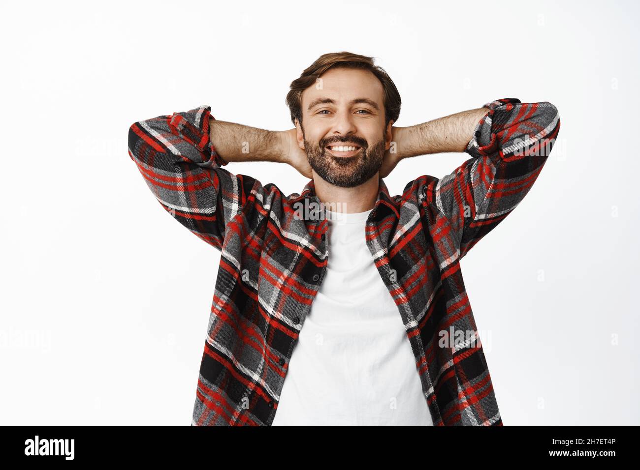 Happy smiling man lying and enjoying weekend, resting, holding hands behind head, being lazy, standing over white background Stock Photo