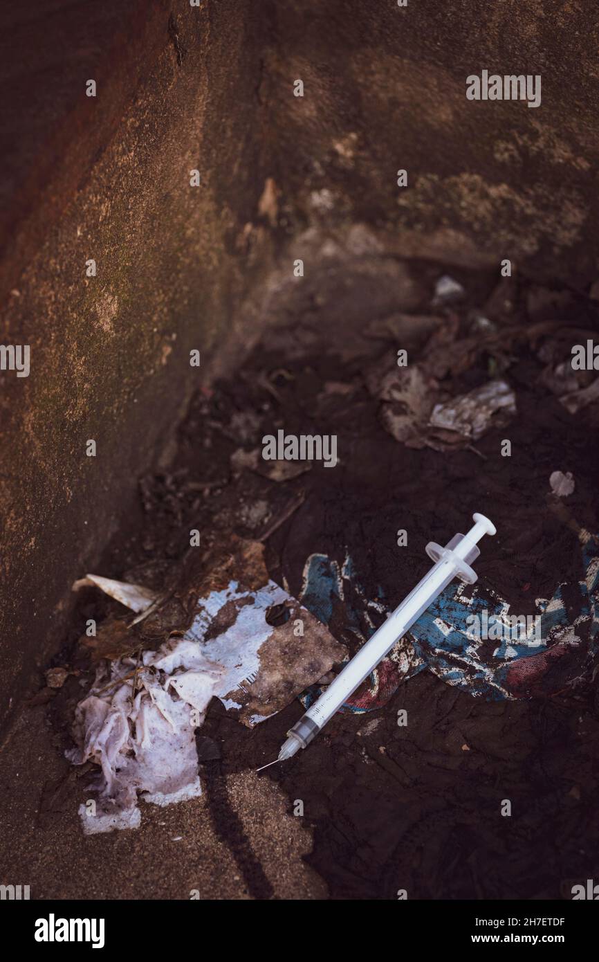 Discarded used hypodermic needle in gutter Stock Photo
