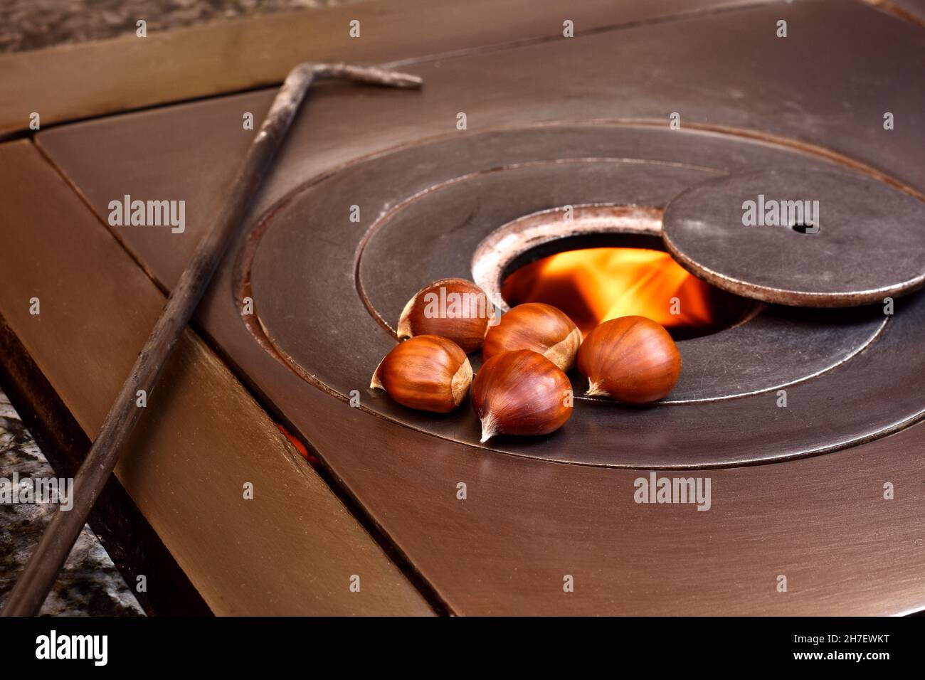 Photograph of some chestnuts over a charcoal stove fire.The photo has a vintage style and is taken in horizontal format. Stock Photo