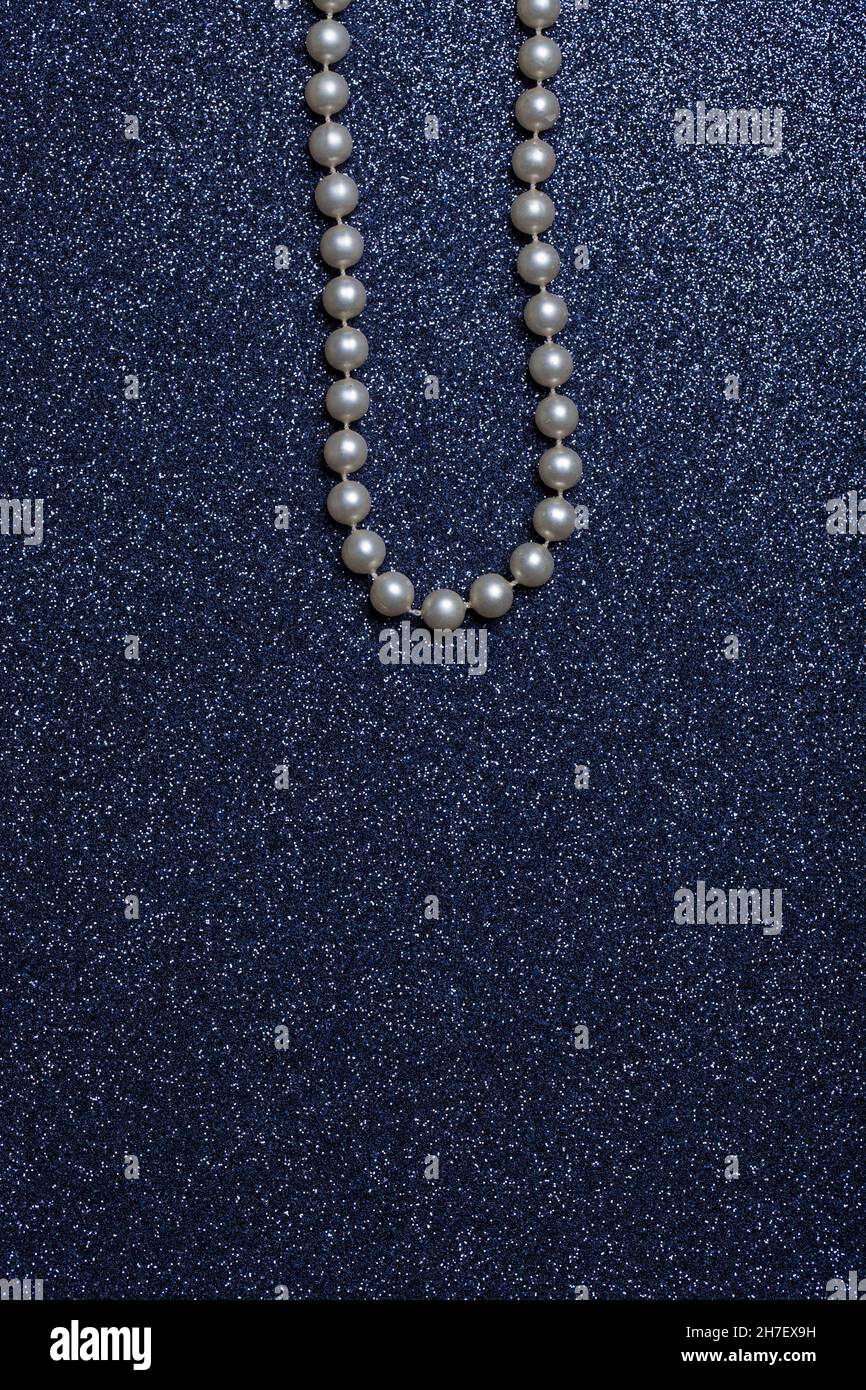 Plastic pearl necklace on blue glittering background. Stock Photo