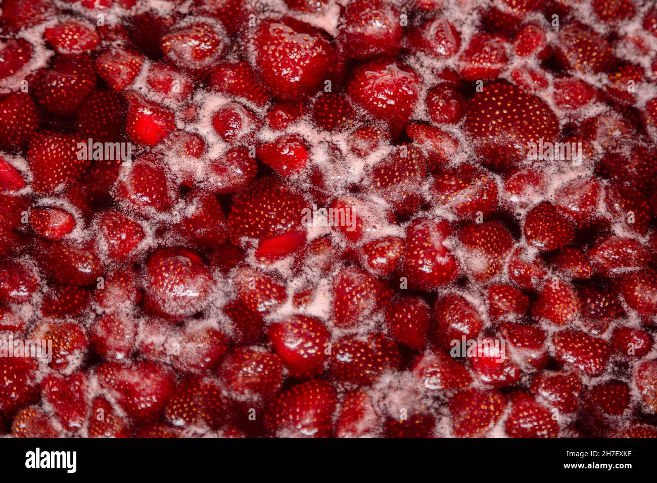 Process of making homemade strawberry jam. Red sweet syrup boiling on the stove closeup. Strawberry jam looks very appetizing. Stock Photo
