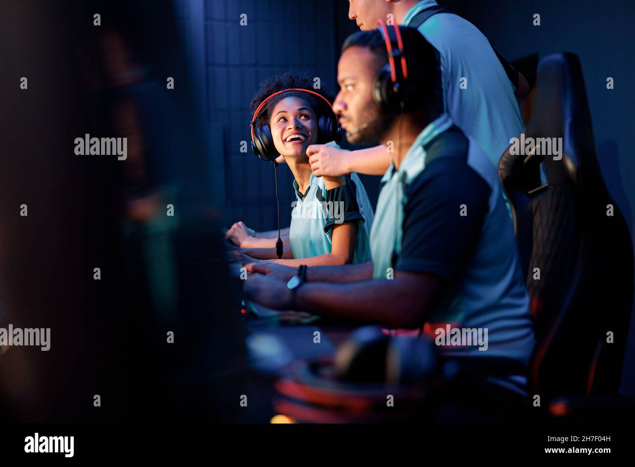 Skilful player assists friend to pass video game indoors Stock Photo