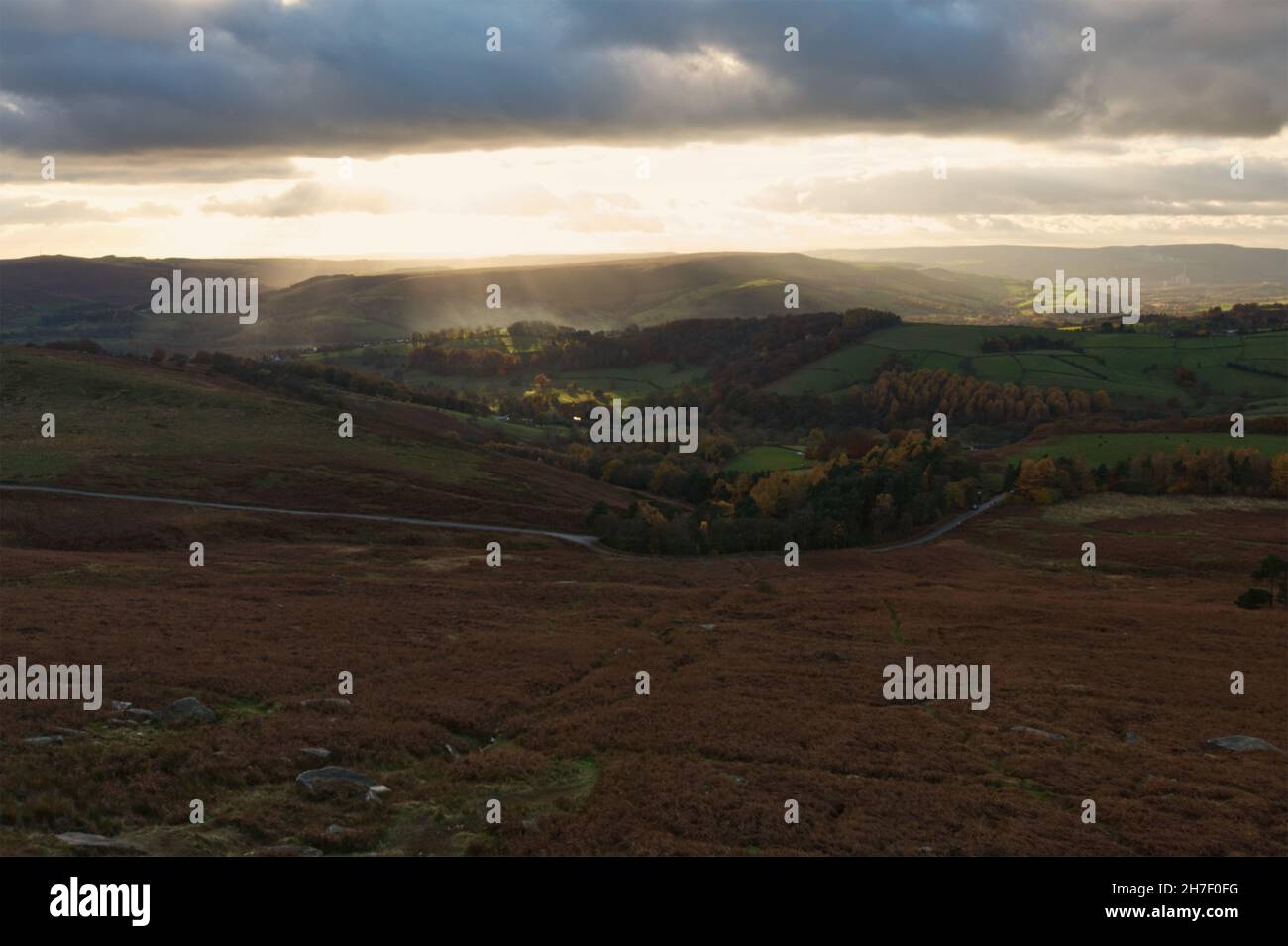 Looking out from Stanage Edge in the Peak District as the sun sets over the valley beneath. Stock Photo